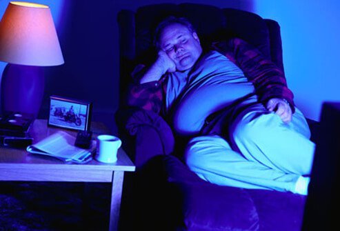 Một người đàn ông ngủ kém vệ sinh đang ngủ gật trước tivi.